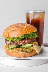 Tasty burger, sauce and cola drink on table