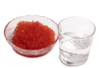 Red caviar lies in glass bowl and vodka. Isolated object on a white background