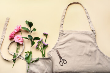 Apron, flowers and scissors on color background