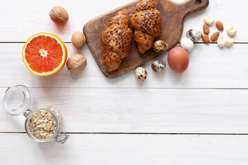 Healthy food: grapefruit, eggs, nuts and cereal on white wood background, top view