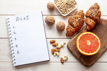 Diet plan on white wood background. Organic food: grapefruit, cereal, nuts and bakery products, top view