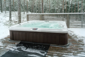 Modern outdoor hot tub on a wooden deck in the cold winter day, Finland.