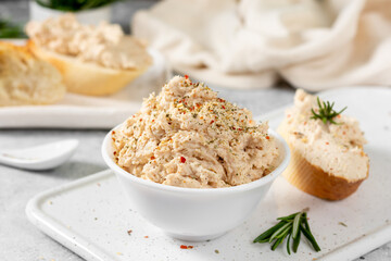 Chicken pate in a white bowl on a light gray kitchen table. Homemade chicken fillet pate with seasonings on a light background
