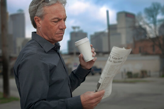 Man drinking coffee and reading a newspaper