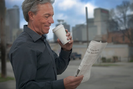 Man drinking coffee and reading a newspaper