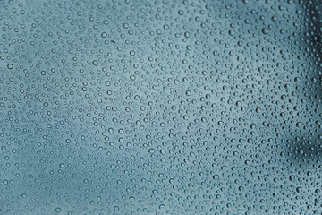 Close up of rain drops on a car glass in a cloudy day from the interior of the car