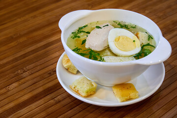 Broth with chicken fillet, egg, croutons and herbs. Close-up, selective focus