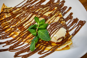 Pancake with a scoop of ice cream and chocolate. Close-up, selective focus