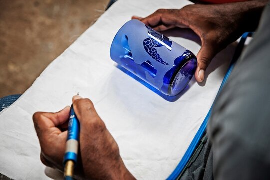 Ecuador, Galapagos Islands, Man etching design into glass bottle cup in artisan workshop