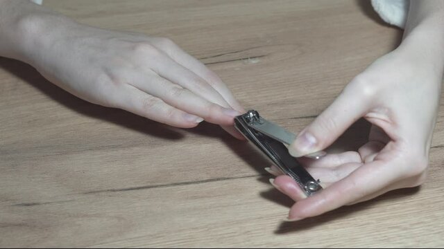 Woman makes herself a manicure at home, cuts her nails with steel clippers, close-up, 4k. Nails cutting process.