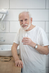 Gray-haired man in white tshirt in the bathroom