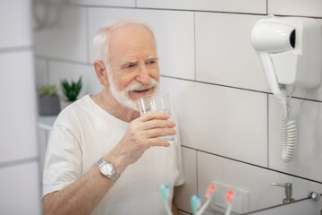 Gray-haired man in white tshirt in the bathroom