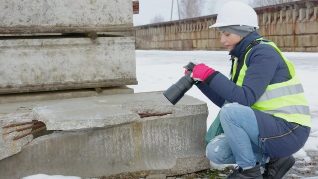 Woman civil engineer taking pictures of damaged construction concrete blocks
