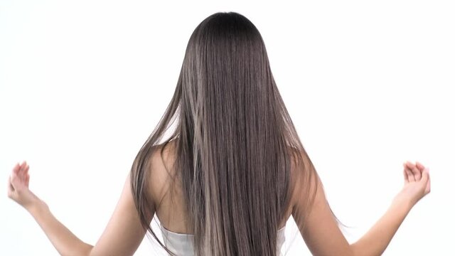 Woman moves long hair. Rear view. Girl shakes long straight hair. Female model is fluttering hair.  Slow motion footage. Rear view.