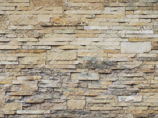 Wall with decorative beige embossed cladding of narrow granite tiles with gray spots. Not seamless texture