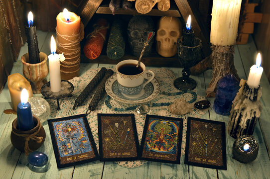 Fortune telling ritual with tarot cards, burning candles, cup of tea and crystals on wooden table.