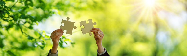 Human hand with piece of jigsaw outdoors on the nature background.
