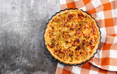 Homemade leek and cheese pie in a glass baking dish on a dark grey background. Top view, flat lay