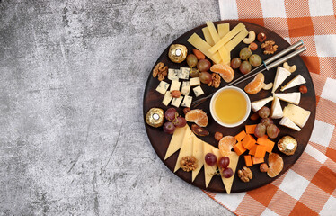 Cheese board served with honey, grapes, berries and nuts on a dark background. Top view, flat lay