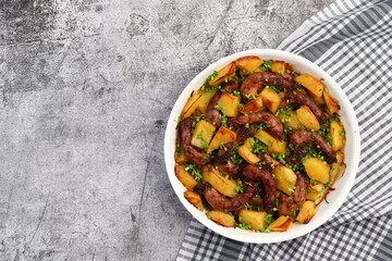 Oven Baked chicken necks with potatoes in a white baking dish on a dark grey background. Top view, flat lay.