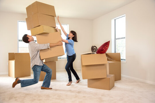 Couple moving into new house, man carrying several boxes