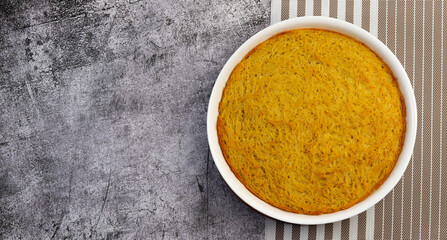 Traditional Noodle and Egg Casserole in a white baking dish on a dark grey background. Top view, flat lay