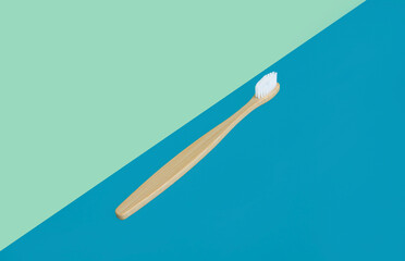 Bamboo toothbrush on a blue and green background at an angle. Oral cavity care. The concept of eco-friendly toothbrush disposal and plastic-free recycling. copy space