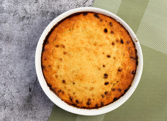 Curd casserole with raisins in a white baking dish on a dark grey background. Top view, flat lay
