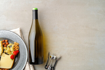 Wine bottle and plate of cheese on gray surface flat lay