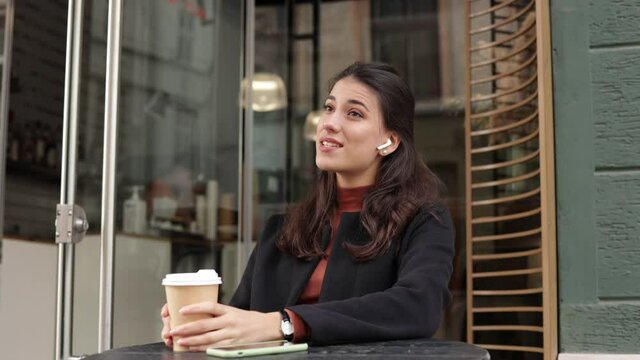 Beautiful business woman speaking mobile phone using handsfree sitting in cafe. Closeup smiling lady talking smartphone with colleagues or business partners. Portrait of beautiful female freelancer