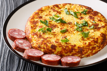Delicious fried mashed potato pancakes with bacon and sauerkraut served with sausages close-up in a plate on the table. Horizontal