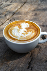 Hot coffee, cappuccino in a white mug placed on the table.
