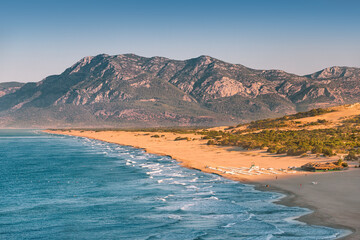 Morning view of the Mediterranean seacoast at the Patara beach during high tide with waves. High mesmerizing mountain in the background. Hidden natural wonders of Turkey