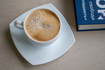 Cup of Morning cappuccino coffee with milk and blue book photography
