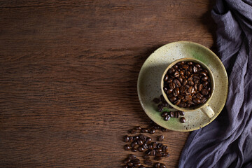 Top view above of Black coffee seed for morning menu in brown ceramic cup with coffee beans roasted on old wooden table background. Flat lay with copy space.