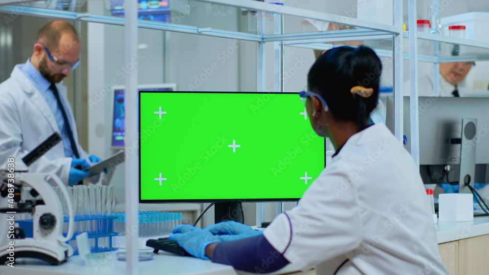 Aufkleber african doctor working at computer with green screen in modern equipped lab. multiethnic team of mic