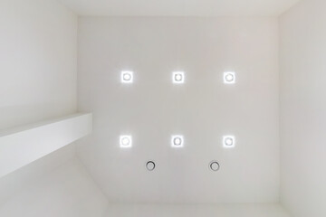 suspended ceiling with halogen spots lamps and drywall construction in empty room in apartment or...