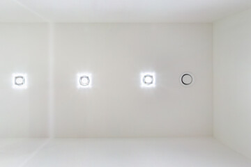 suspended ceiling with halogen spots lamps and drywall construction in empty room in apartment or...