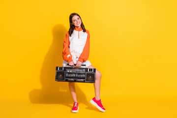 Photo portrait full body view of woman holding boombox in two hands isolated on vivid yellow colored background