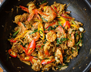 Top view of Thai stir fried shrimps with yellow curry powder in a pan, Close up Thai food in a pan