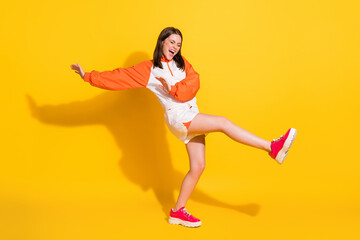 Full length photo portrait of woman standing on one leg kicking screaming isolated on vivid yellow...