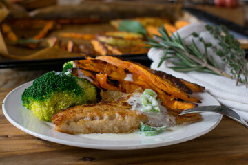 pan-fried fish with sweet potato fries and broccoli and white sauce