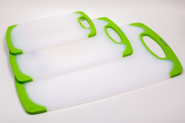 Set of white kitchen cutting boards with green handles for cooking.