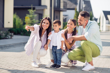 Photo of happy positive smiling family mom dad shoolgirl showing way point finger copyspace for little son outside outdoors