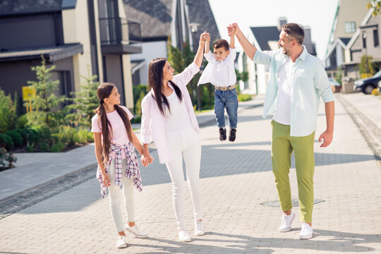 Photo Of Sweet Funky Family Hold Boy Up Walk Around Near Home Wear Casual Cloth Outside