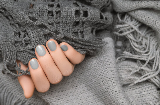 Female Hand With Silver Nail Design. Silver Glitter Nail Polish Manicure. Woman Hand On Gray Woolen Background.