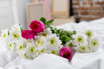 Chrysanthemums and tulips on white bedding on blurred foreground