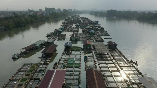 slow drone shot flying over floating fish farming community in Bien Hoa on the Dong Nai river, Vietnam on a sunny day