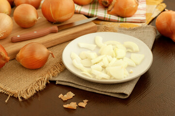 Cooking onion dishes. Lots of onions on the kitchen table. Sliced onions on a plate. Vegetables in the form of onions.