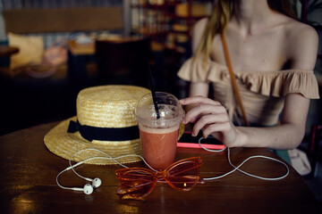 A woman sits in a restaurant with headphones a glass of fresh glasses leisure pastime